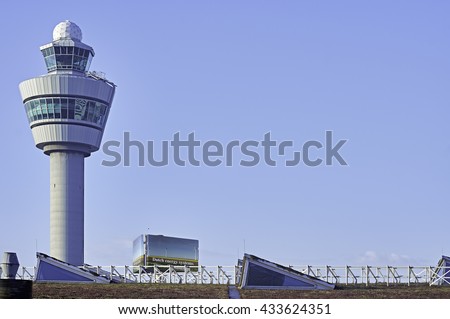 Airport control tower Amsterdam Schiphol in the early morning light against a blue sky.  Lots of copy space.                          