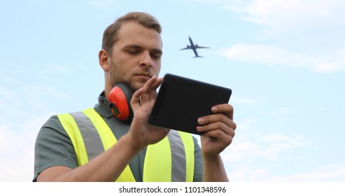 Airport Ground Serviceman Job Work Using Digital Tablet While Airplane Passing Overhead