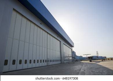 Airport Hangar From The Outside With Big Tall Doors. Bright Blue Sky.