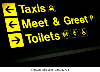 Airport Information Sign Light Panel Giving Directions In Arrivals Lounge For Taxi, Meet And Greet And Toilets.