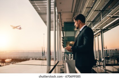 Airport Lounge Balcony And Looking At Airplane Take Off. Business Man Waiting For His Flight.