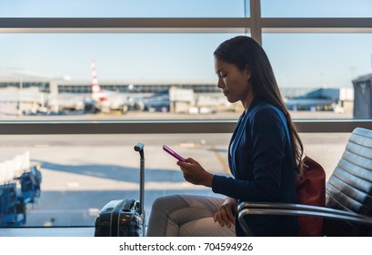 Airport Phone Travel Woman Using Mobile Phone In Business Class Lounge Waiting For Plane Flight Texting Sms Message On Smartphone. Technology And Travel People Frequent Flying Lifestyle.