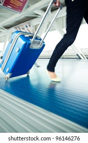 Airport Rush: People With Their Suitcases Walking Along A Corridor (motion Blurred Image; Color Toned Image)