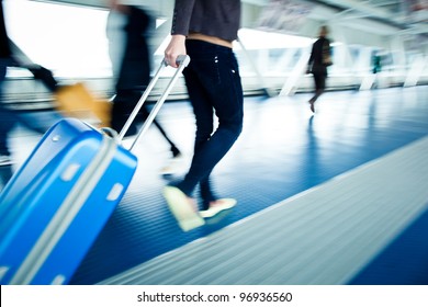 Airport Rush: People With Their Suitcases Walking Along A Corridor (motion Blurred Image; Color Toned Image)