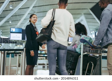 Airport Staff During Pandemic Helping Traveler Family At Boarding Gate. Ground Staff At Airport Assisting Tourist In Face Masks During Pandemic.