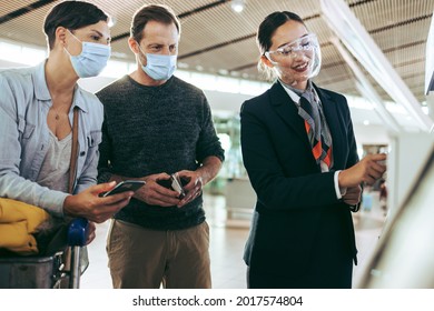 Airport Staff Helping Family With Self Service Check-in During Pandemic. Passenger Family Helped By Airlines Attendant At Airport In Pandemic.