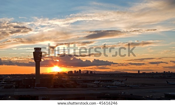 Airport at sunset with city\
skyline.