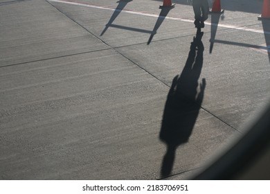 Airport Tarmac With Shadow Of Airport Worker With Orange Traffic Cones