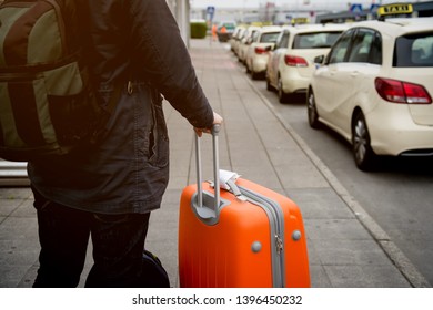 Airport taxi. Tourist is waiting a taxi car in airport while standing with a big suitcase. Business trip or vacation,