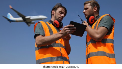 Airport Team Activity, Men Work On Digital Tablet, Talk On Walkie Talkie Collaborating With Air Traffic Control Tower, Airplane Flying Over Aircrew Controllers Ground Crew, Aircraft Passing Overhead
