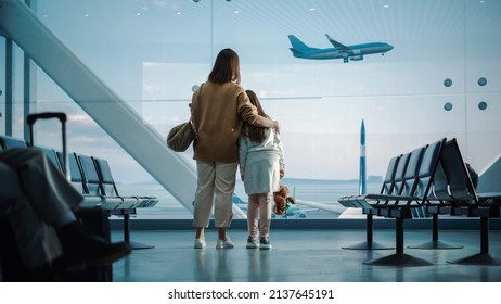 Airport Terminal: Beautiful Mother And Cute Little Daughter Wait For Their Vacation Flight, Looking Out Of Window For Arriving And Departing Airplanes. Young Family In Boarding Lounge Of Airline Hub