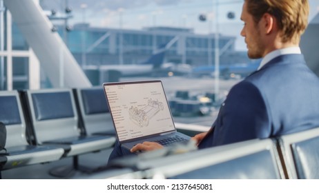 Airport Terminal: Businessman is Reviewing a Blueprint on Laptop While Waiting for His Plane Flight. Entrepreneur Does Online Remote Work in Boarding Lounge of Airline Hub. Over the Shoulder