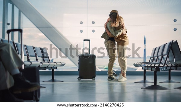 Airport Terminal Family Reunion: Beauitful Couple\
Meets at the Boarding Lounge. Smiling Girlfiend Meets the Love of\
Her Life after Long Parting and Hugs and Dances with Her Handsome\
Partner