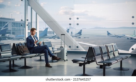 Airport Terminal Flight Wait: Smiling Businessman Uses Digital Tablet Computer for e-Business, Browsing Internet with App. Traveling Entrepreneur Work Online, Sitting in Boarding Lounge of Airline Hub