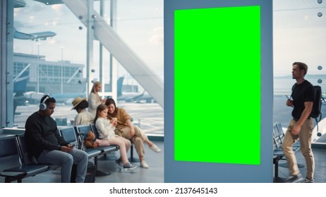 Airport Terminal: Green Screen Advertising Billboard, Arrival Display With Chroma Key, Mock-up AD Space. Backgrond: Diverse Crowd Of People Wait For Their Flights In Boarding Lounge Of Airline Hub