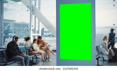 Airport Terminal: Green Screen Advertising Billboard, Arrival Display With Chroma Key, Mock-up AD Space. Backgrond: Diverse Crowd Of People Wait For Their Flights In Boarding Lounge Of Airline Hub