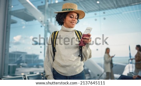 Airport Terminal: Happy Traveling Black Woman Looks Around Searching Flight Gates and Plane, Uses Smartphone, Checking Trip Destination on Internet. African American Female Wondering on Vacation