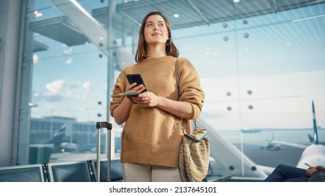Airport Terminal: Happy Traveling Caucasian Woman Waiting at Flight Gates for Plane Boarding, Uses Mobile Smartphone, Checking Trip Destination on Internet. Smiling White Female in Airline Hub - Shutterstock ID 2137645101