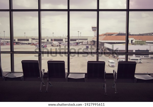 Airport terminal silhouette seats resting for pedestrian\
people waiting plane to arrive with big window plane view airport\
plane parking traffic, traveling tourism transportation immigration\
concept 