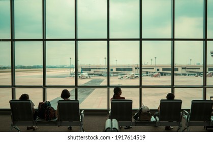 Airport terminal waiting seats for people family silhouette sitting resting waiting for plane to arrive with big window plane view of airport plane parking traffic, travel tourism transport concept