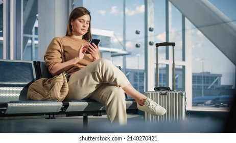 Airport Terminal: Woman Waits for Flight, Uses Smartphone, Browse Internet, Social Media, Online Shopping. Traveling Female Remote Work Online on Mobile Phone in a Boarding Lounge of Airline Hub - Shutterstock ID 2140270421
