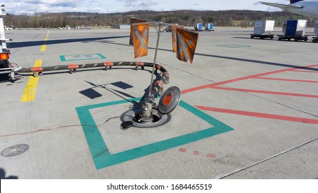 Airport Underground Fuel Storage Tank On Airplane Parking Area. Orange Flags Over Fuel Tank Hole To Warn Other Worker. Fuel Pipeline Connected With Underground Fuel Tank To Refill Aircraft.