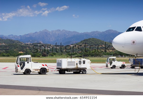 Airport vehicles towing white modern\
aircraft on the parking lot. Airport ground\
operation.