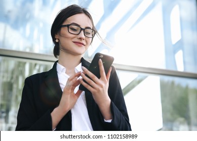 Airport Woman On Smart Phone At Gate Waiting In Terminal. Air Travel Concept With Young Casual Business Woman Sitting With Talking On The Smartphone, Carry-on Hand Luggage Trolley. Beautiful Young.