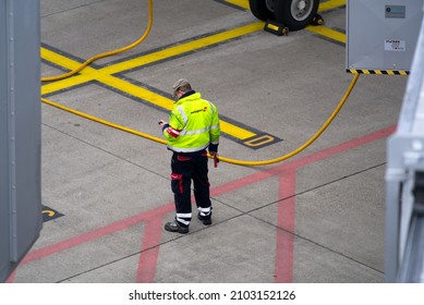 Airport Worker Checking Mobile Device At Zürich Airport On A Cloudy Winter Day. Photo Taken January 2nd, 2022, Zurich, Switzerland.