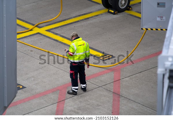 Airport worker checking mobile device at\
Zürich Airport on a cloudy winter day. Photo taken January 2nd,\
2022, Zurich,\
Switzerland.