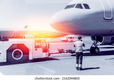 Airport Worker Directs Radio Towing Of Aircraft By Tug To Go Runway. Blue Color Sunlight.