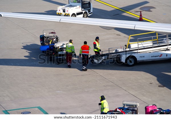 Airport worker loading passenger\
luggage to Swiss Airbus airplane at Zürich Airport on a sunny\
winter day. Photo taken January 19th, 2022, Zurich,\
Switzerland.