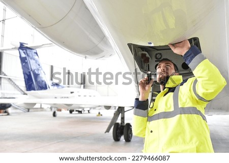 Airport workers check an aircraft for safety in a hangar 