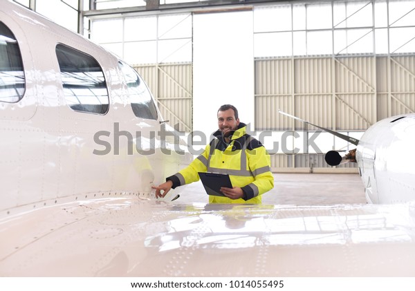 Airport\
workers check an aircraft for safety in a hangar\
