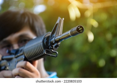 Airsoft Gun Or BB Gun Shooter Holds Airsoft Gun And Aiming It To The Shooting Target Point Ahead, Soft And Selective Focus On The Muzzle, Outdoor Recreational Activity Concept.