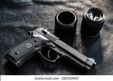 The airsoft gun is placed on a black fabric floor. There is a camera lens placed on the side. Photo taken with natural light