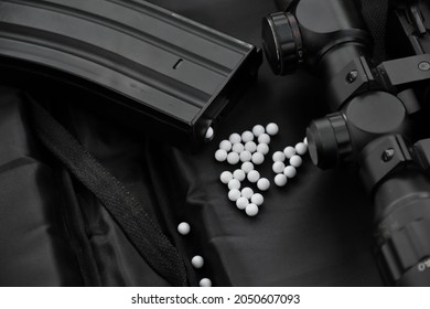 Airsoft gun with round white plastic bullets on a black leather background. Soft and selective focus.