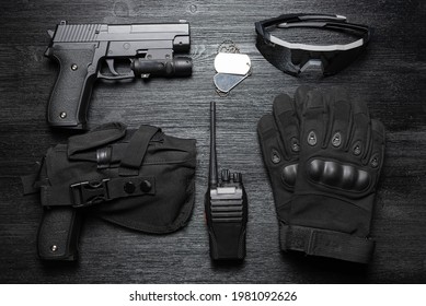 Airsoft Guns, Gloves, Radio Station, Glasses And Soldier Badge On The Black Flat Lay Background.