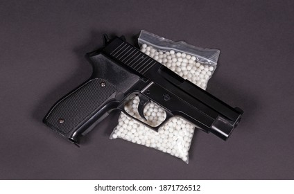 Airsoft pistol with bb bullets on dark background