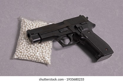 Airsoft pistol with bb bullets on light background