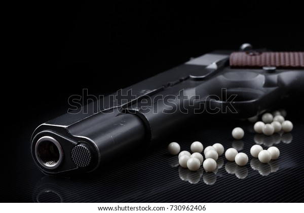 pistolet airsoft avec balles bb sur la surface noire brillante