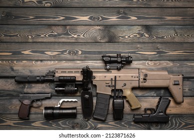 Airsoft weapon and equipment on the wooden flat lay background with copy space.