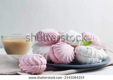 Airy Pink and white Marshmallow dessert zephyr on the table. Meringue dessert with green mint in a grew plate on the white background. traditional Russian sweet dessert. copy space