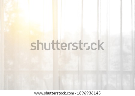 airy or thin and transparent white curtain with texture for see through and soft light on balcony window and close in room for home or hotel interior decor on morning warm sunlight for background