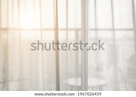 airy or thin and transparent white sheer curtain for see through and soft warm sun light on balcony close window in room for city home or hotel interior decor on morning feel and hot summer background