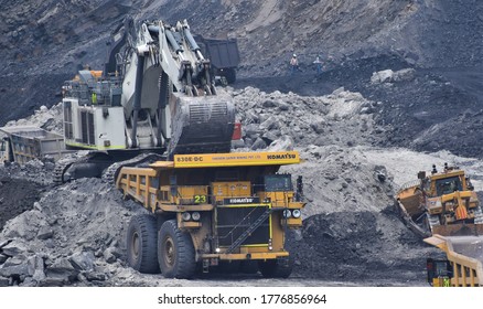 Ajmer, India - July 1, 2020 : Huge Dumper Earthmover Truck carrying minerals at an open pit quarry mines helped by a crane and other heavy machinery.