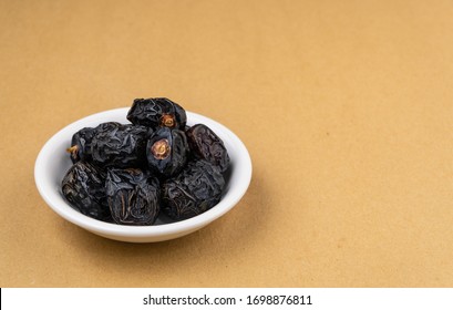 Ajwa Dates or "Kurma Ajwa" in a small plate isolated on light brown background. Prophet dates is one of the special fruit of Arabic .
