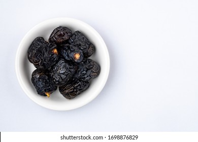 Ajwa Dates or "Kurma Ajwa" in a small plate isolated on white background. Prophet dates is one of the special fruit of Arabic .
