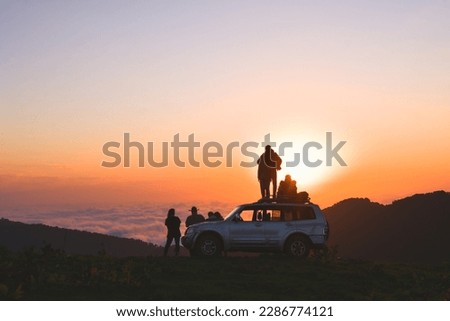 akhmaro, Georgia - 14th august, 2022: Static view friends tour group stand on 4wd rooftop watch sunset together outdoors have fun above clouds in famous travel destination