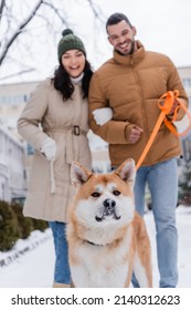 Akita Inu Dog Walking Outside With Happy Blurred Couple